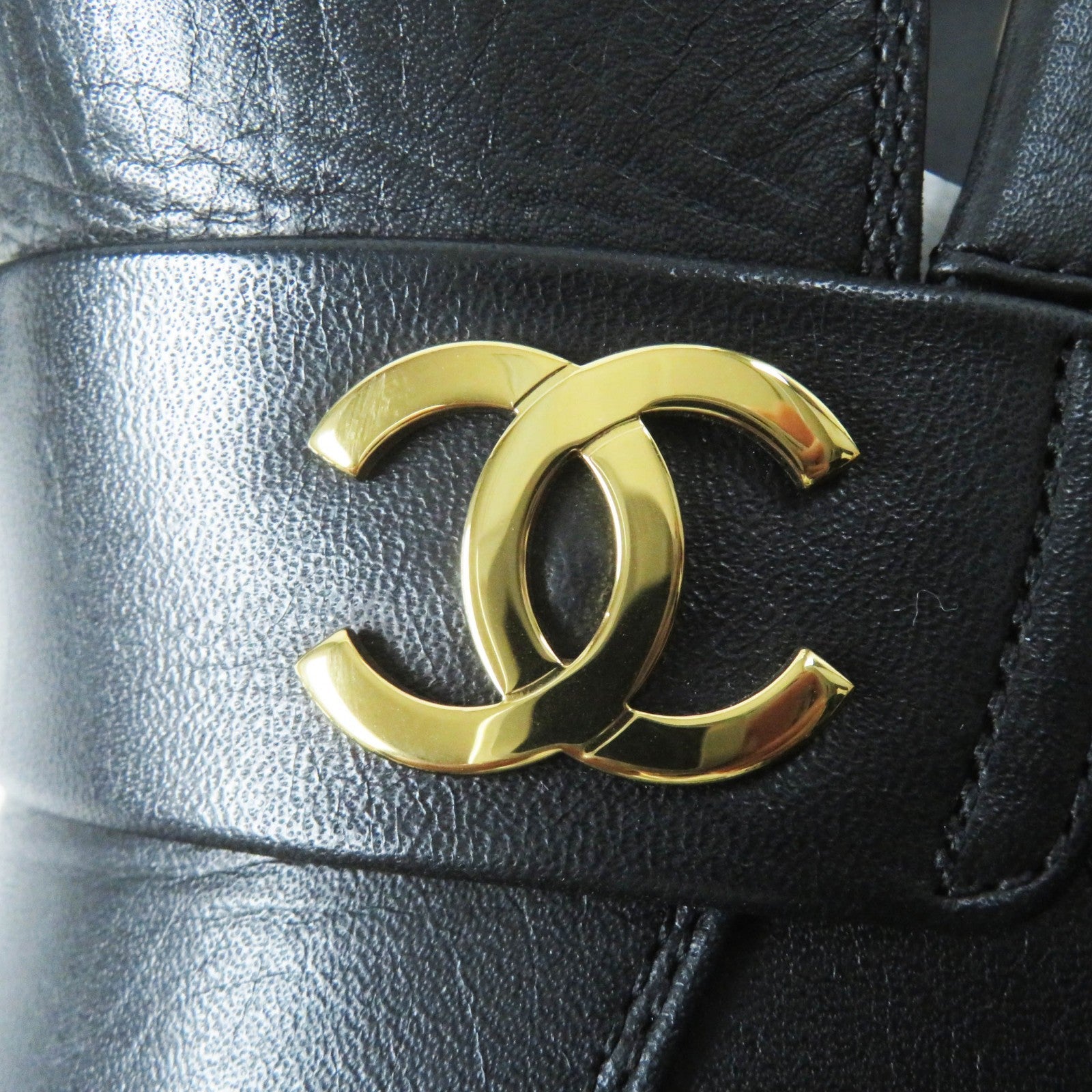Close-up of used Chanel loafers women featuring a gold CC logo on black leather