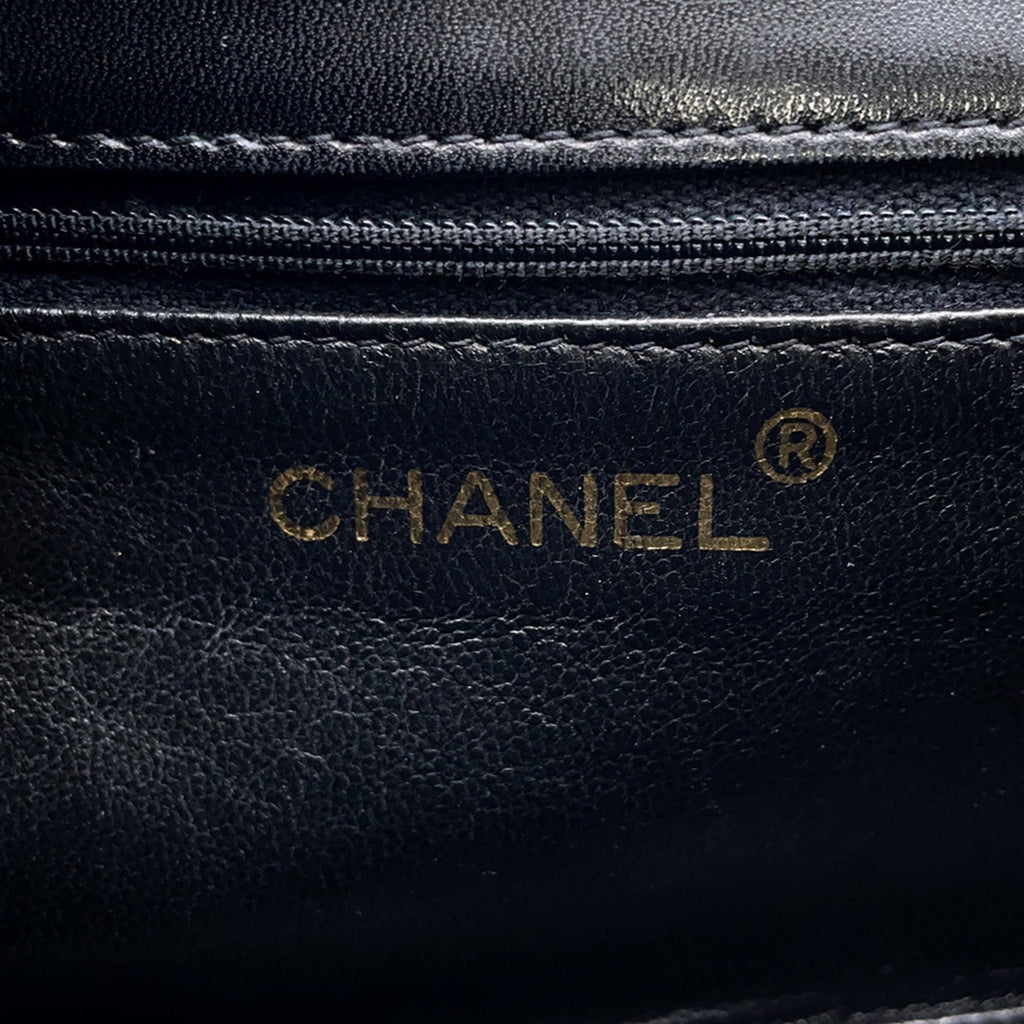 Close-up of the CHANEL Pre-Loved Matelasse Full Flap logo embossed on premium black leather