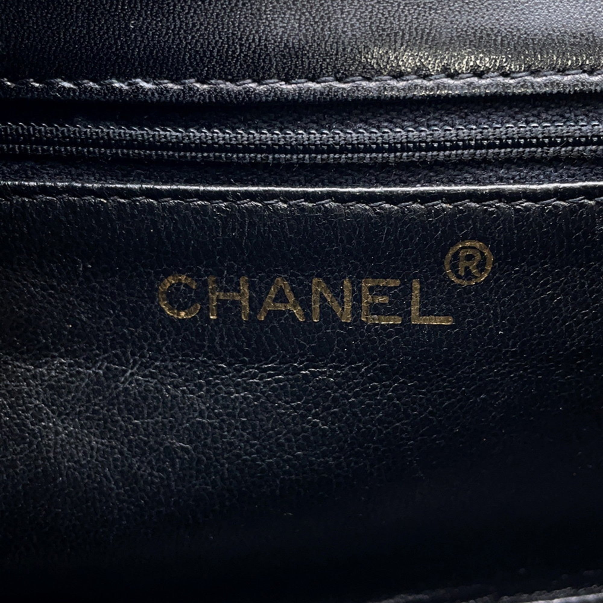 Close-up of the CHANEL Pre-Loved Matelasse Full Flap logo embossed on premium black leather