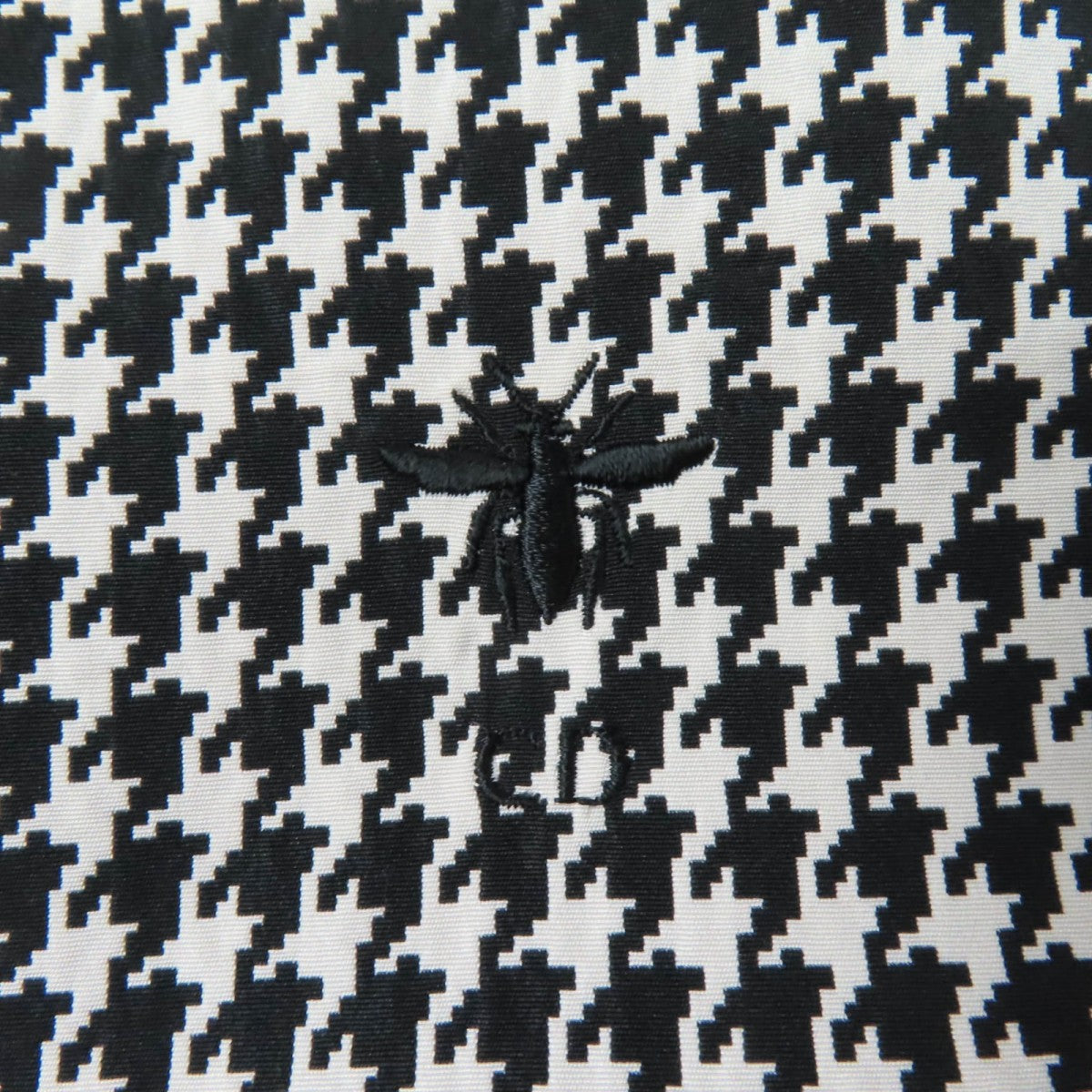 Close-up of Christian Dior pre-loved anorak fabric featuring a houndstooth pattern and embroidered bee design