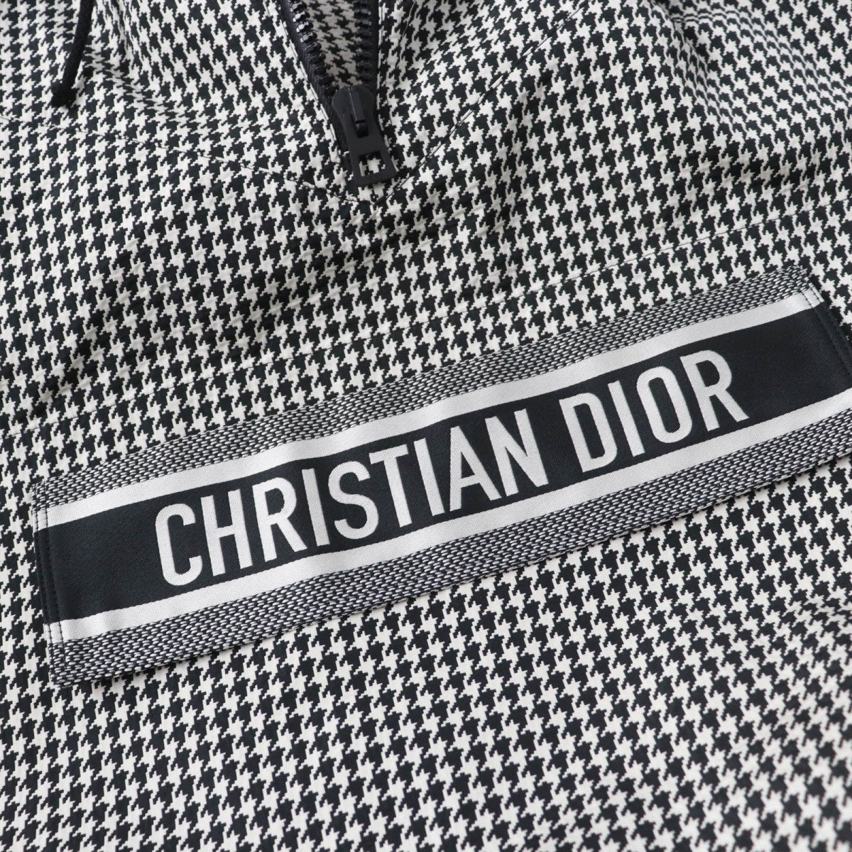 Close-up of Christian Dior pre-loved anorak featuring a bold logo and houndstooth pattern