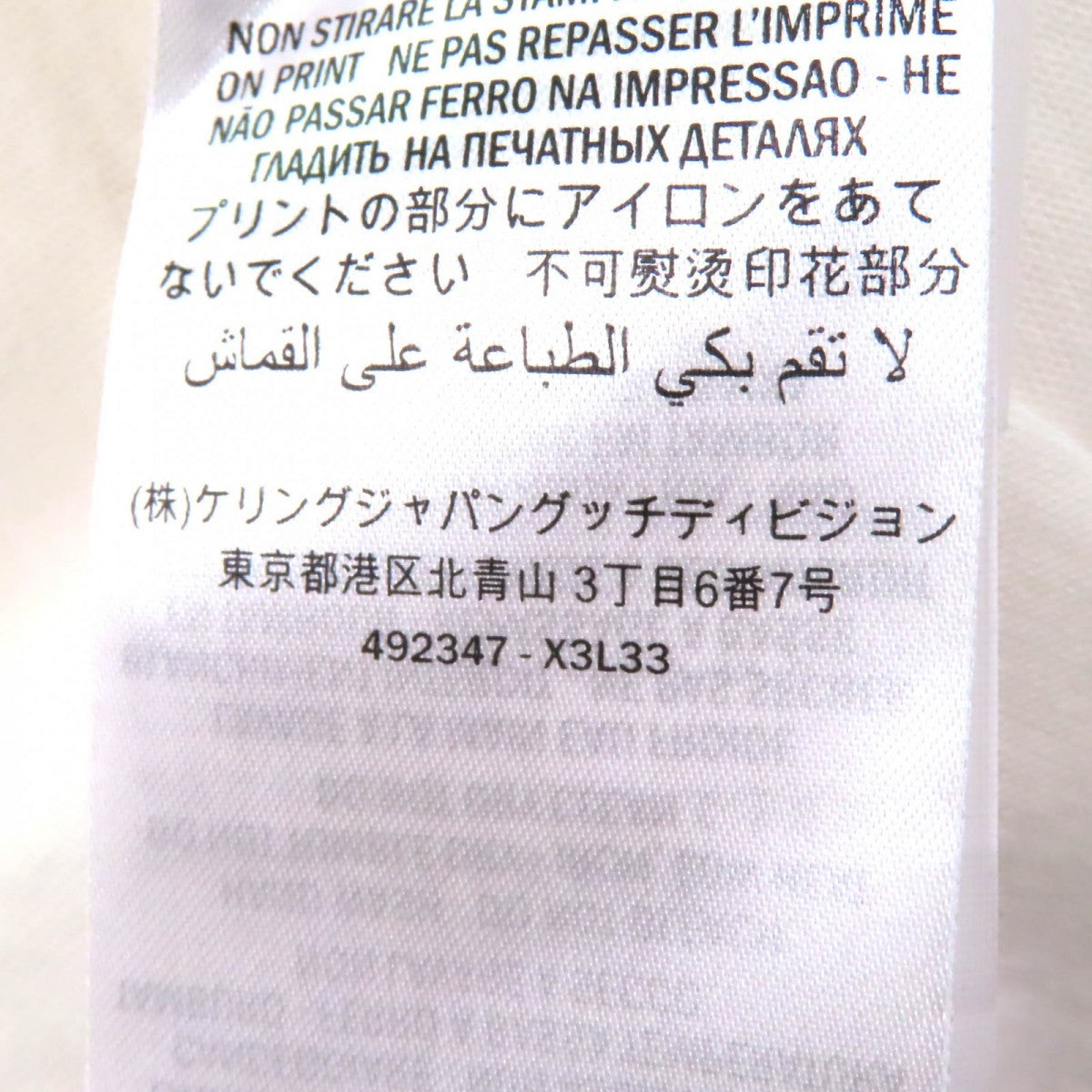 Pre-owned Gucci t-shirt tag showcasing care instructions and brand details on a white fabric
