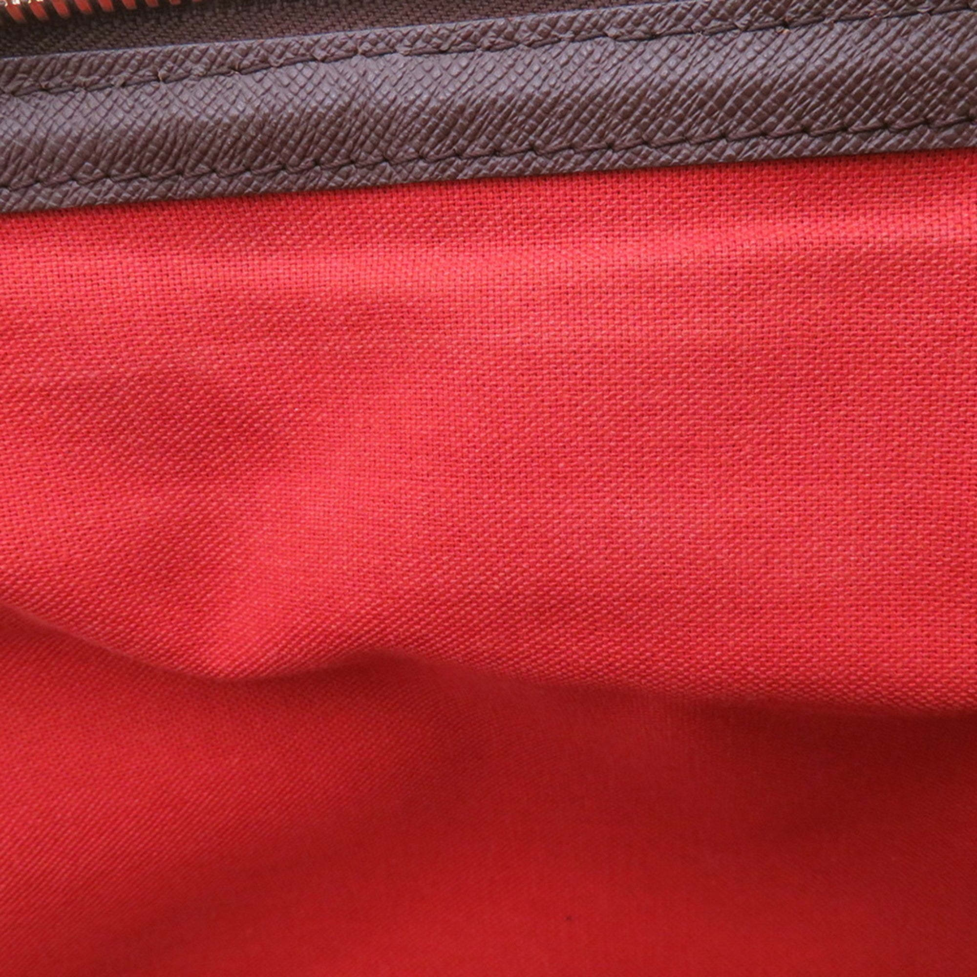 Interior view of authentic Louis Vuitton Belem MM bag for sale showcasing red lining and quality stitching