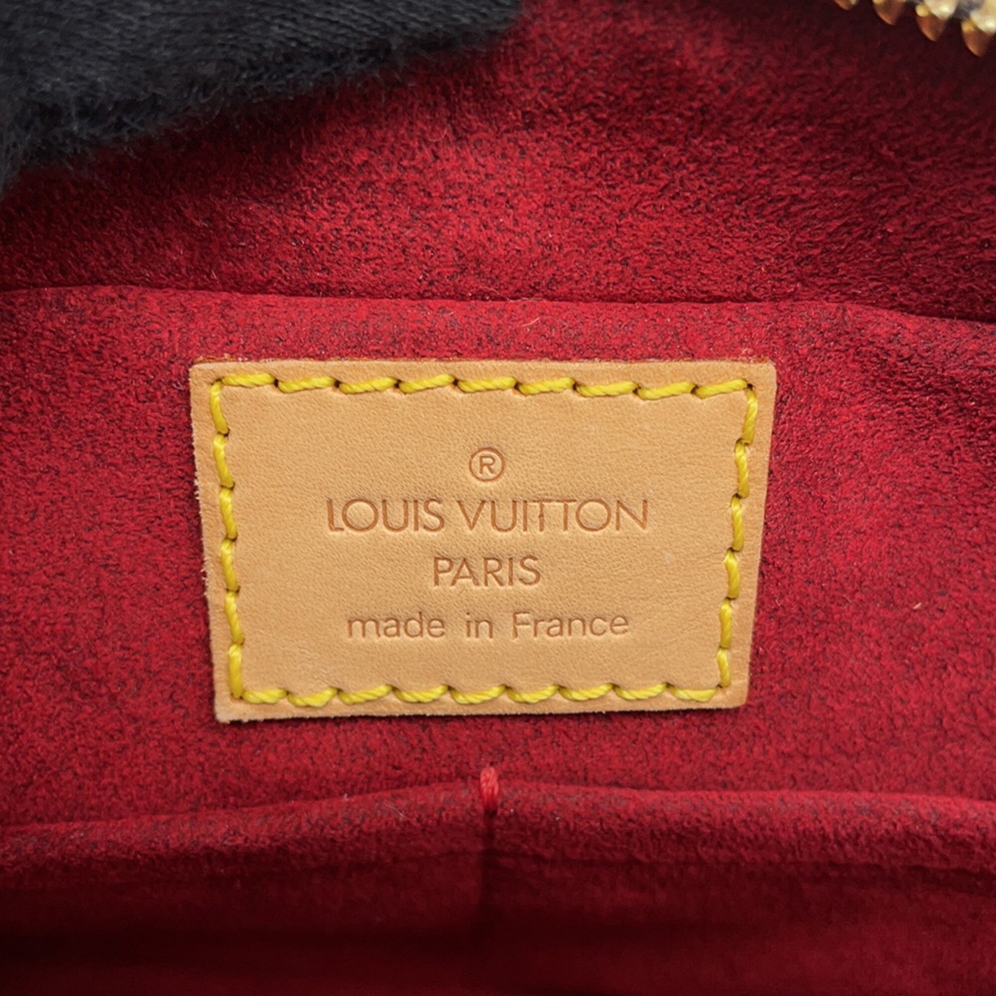Interior label of a Louis Vuitton bag, used like new with red suede lining and yellow stitching