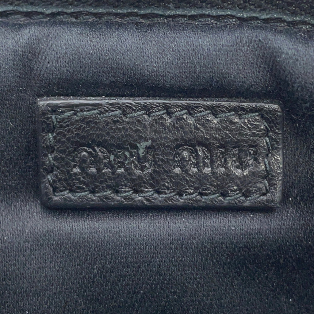 Close-up of MIU MIU Pre-Loved Swallow Pattern Bag logo embossed on leather for authenticity