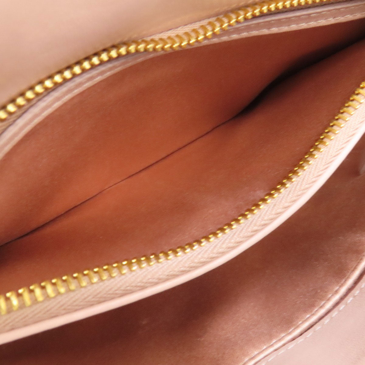 Interior of a MIU MIU pre-owned bag showing a spacious compartment with gold zipper detail