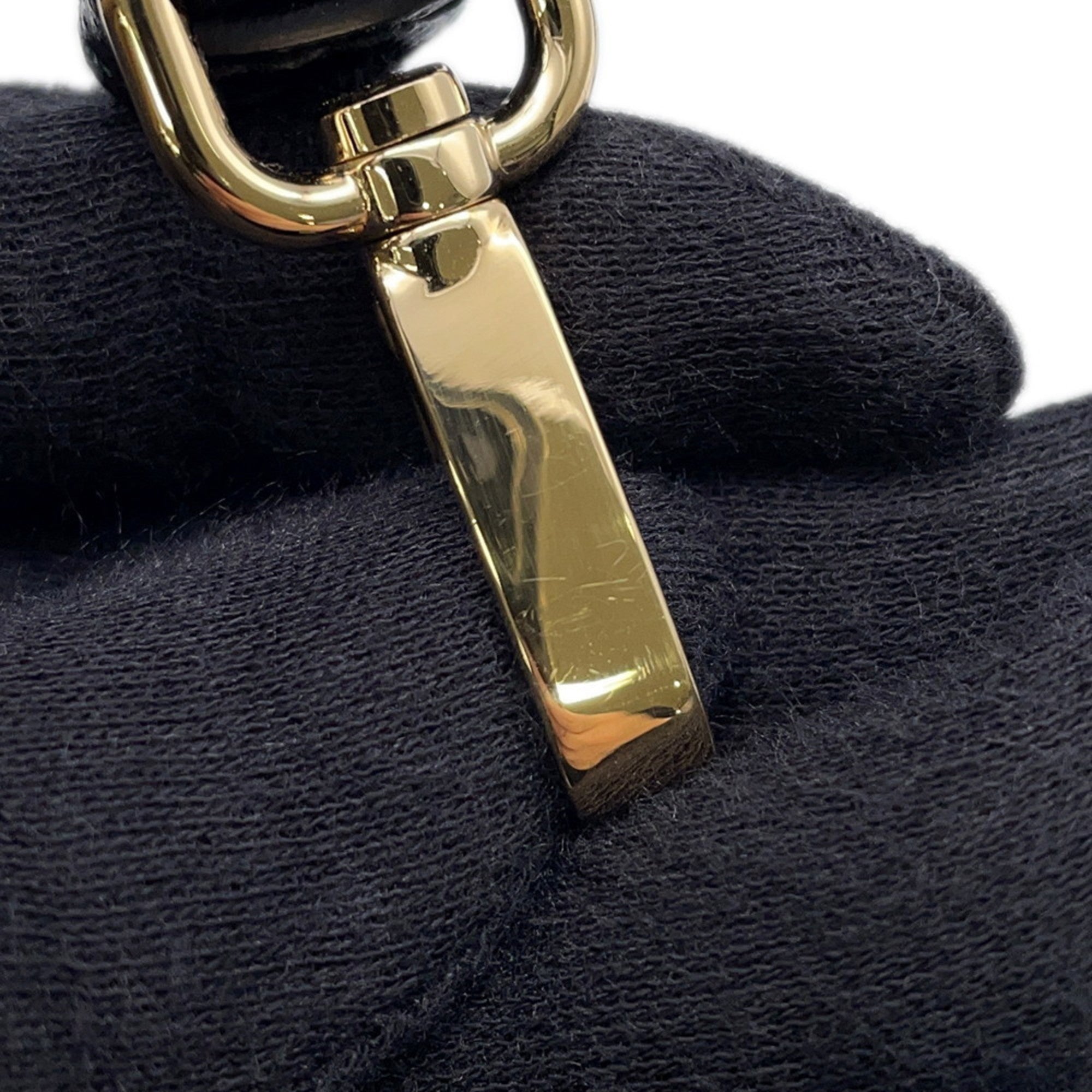 Close-up of MANSII mob wife accessory featuring a polished gold clasp on a black surface