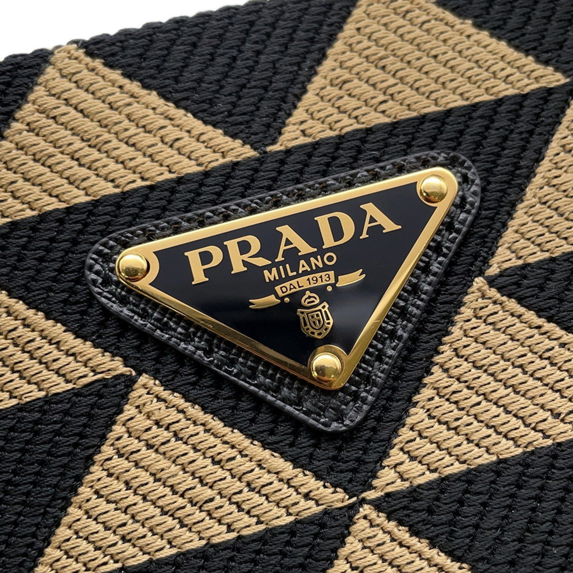 Prada handbag featuring a bold geometric design and a gold logo plaque for the stylish mob wife
