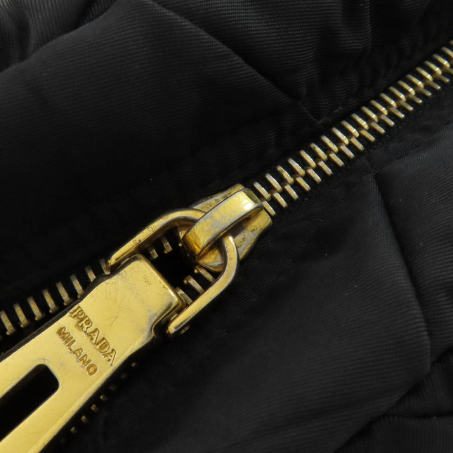 Close-up of a PRADA pre-owned bag zipper with gold hardware and black fabric detailing