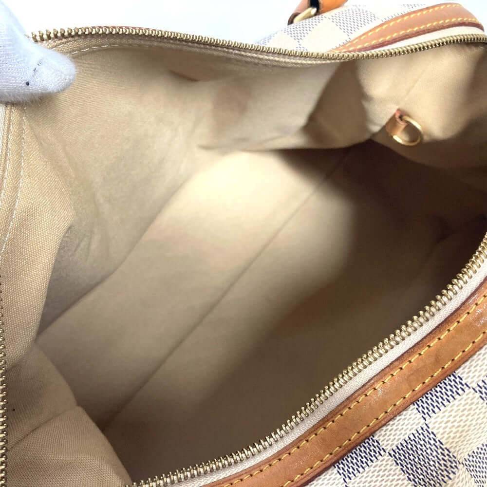 Interior of a pre-owned Louis Vuitton bag featuring a spacious, beige lining for optimal organization