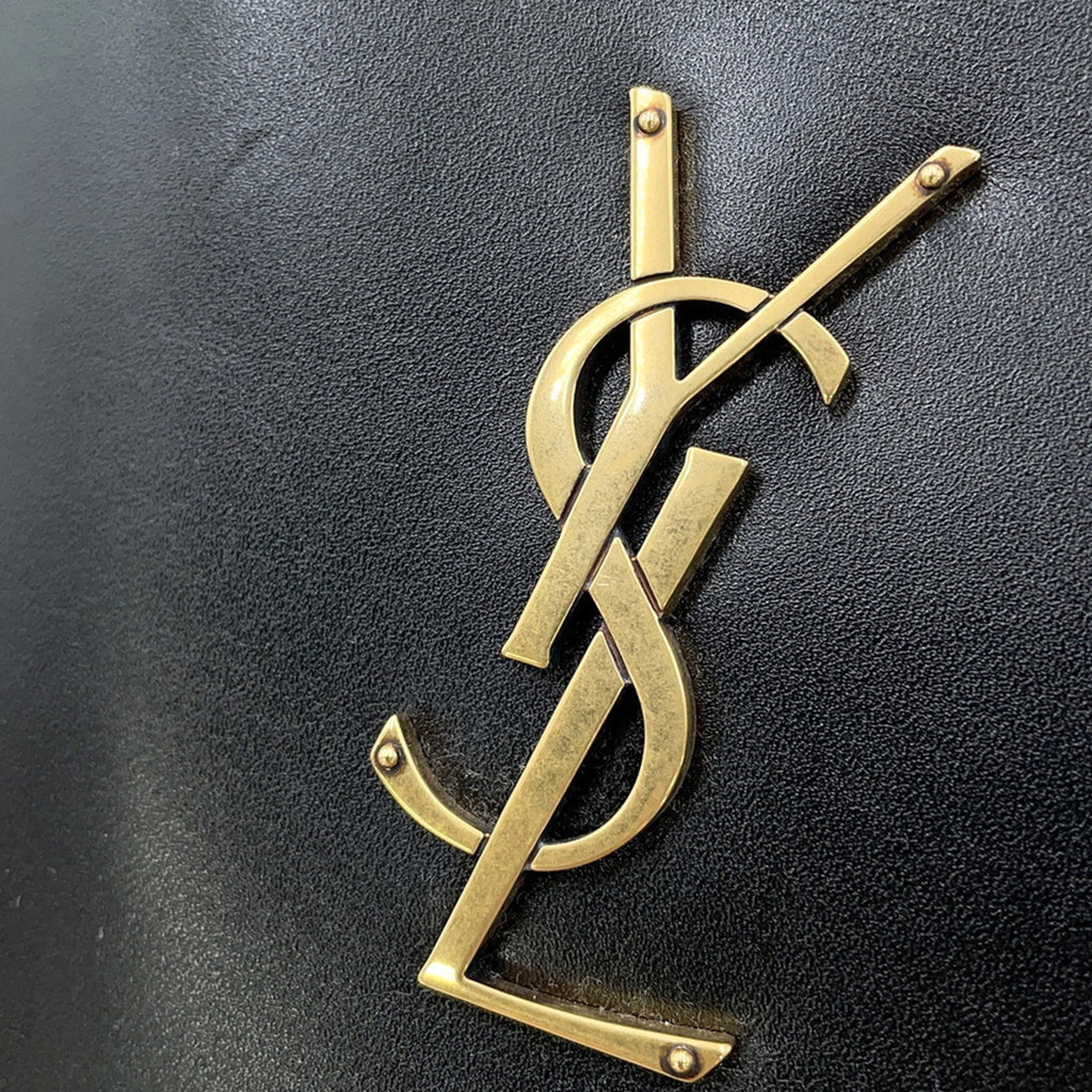 Close-up of the gold YSL logo on SAINT LAURENT Seria Mini 2 way bag showcasing luxury fashion details