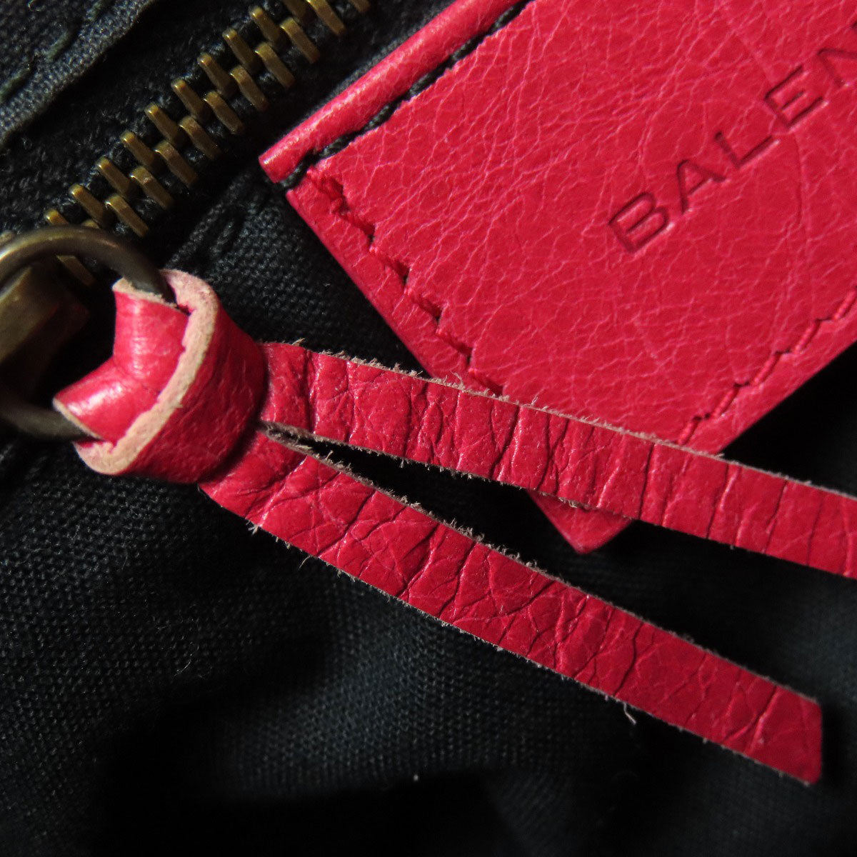 Close-up of a BALENCIAGA bag tag and zipper pull, ideal for second hand fashion lovers