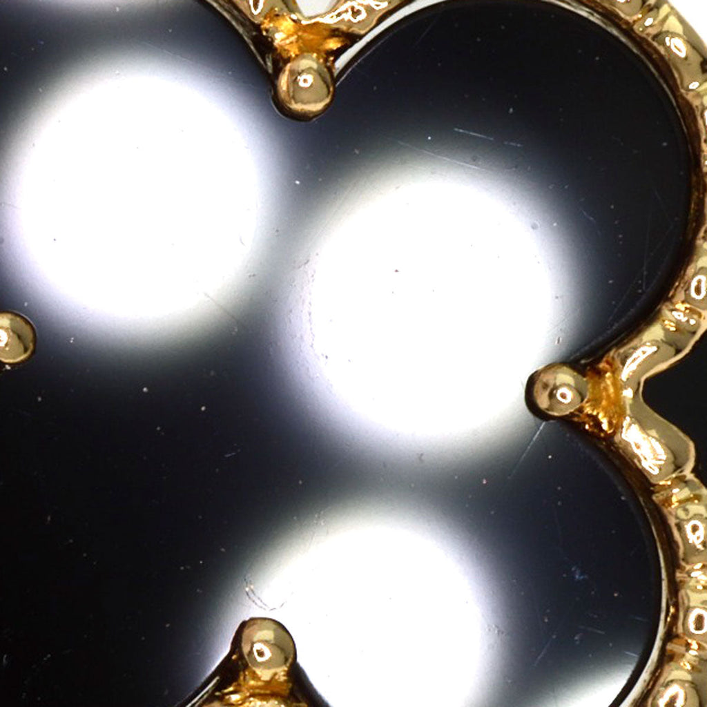 Close-up of a used Van Cleef 18K gold bracelet featuring a black onyx clover design